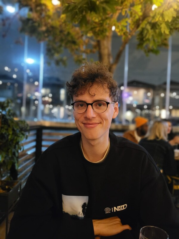 A researcher with black glasses and curly blond hair